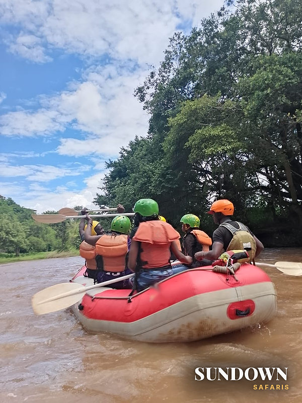 Sundown guests paddling a raft down the river