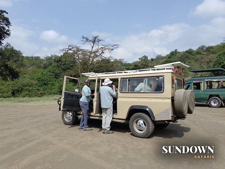 A Sundown Safaris guide with guests beside the safari vehicle